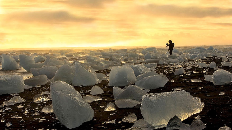 homem a fotografar o por-do-sol na diamond beach na islandia